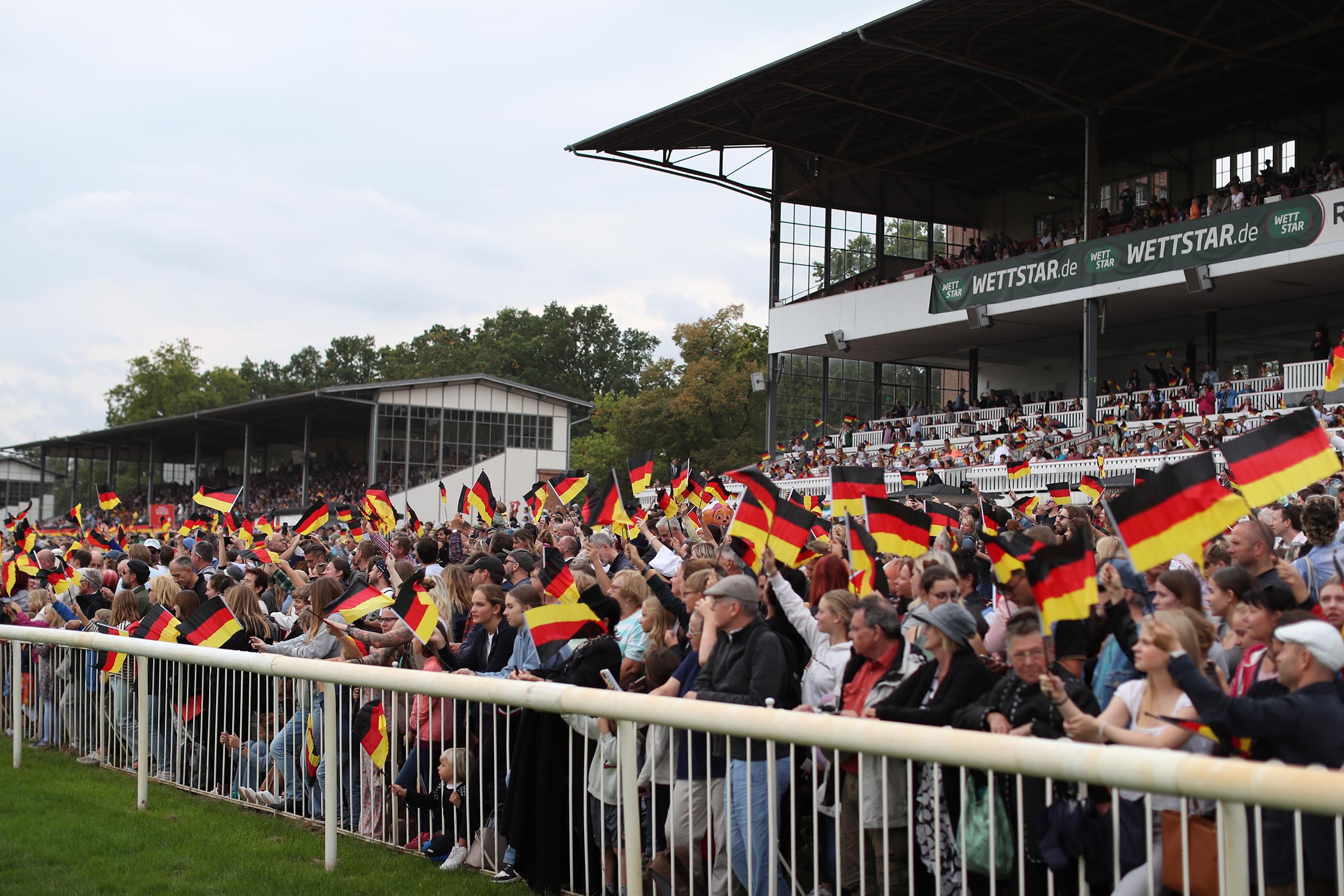 Rennbahnbesucher schwenken deutschland-Fahnen am Renntag der Deutschen Einheit